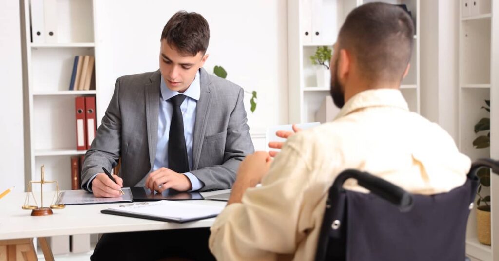 Man in wheelchair meeting with male lawyer to review public liability claim | Arnold Dallas McPherson Injury Lawyers