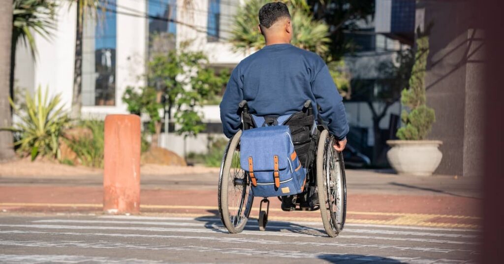 Man in wheelchair moving through a zebra crossing | Arnold Dallas McPherson Injury Lawyers