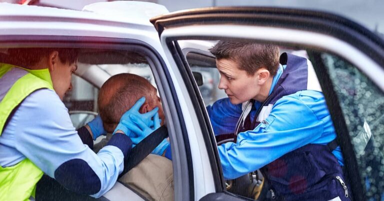 Paramedics treating injured victim in the driver's seat of a car after an accident | Arnold Dallas McPherson Injury Lawyers