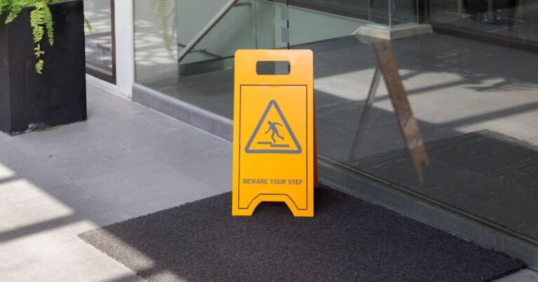Caution sign reading 'Beware Your Step' outside a business lobby | Arnold Dallas McPherson Injury Lawyers